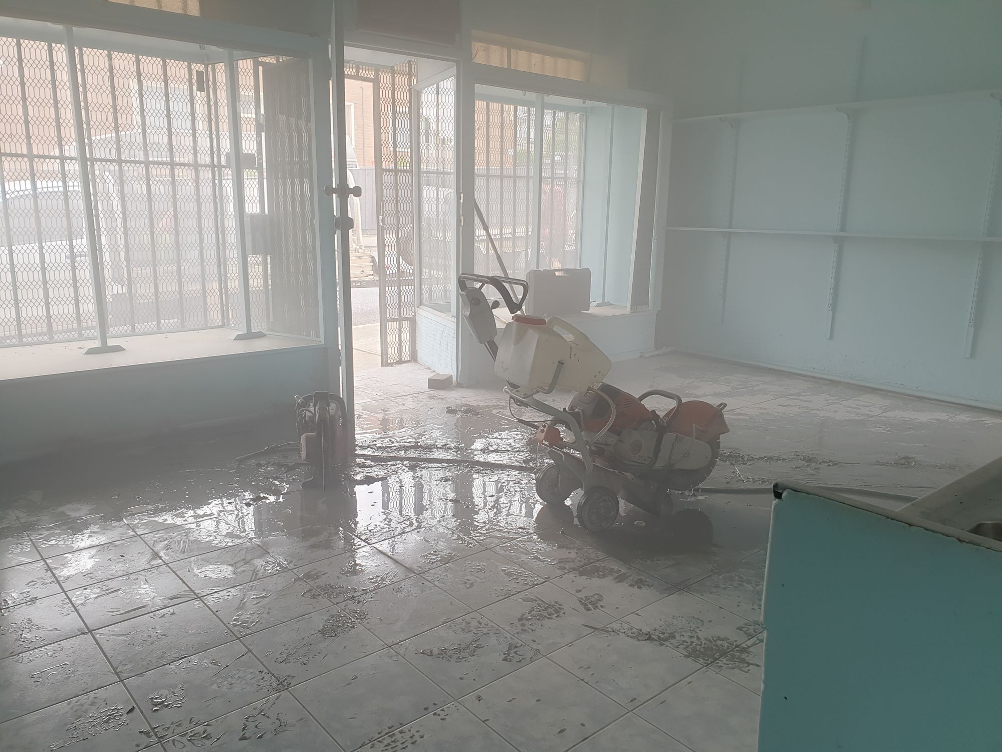 Concrete cutter in the middle of a room, a lot of dust in the air