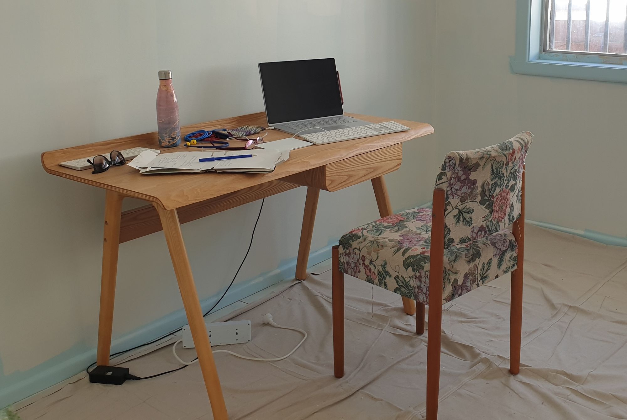 A desk with a laptop, flattened boxes and a pen