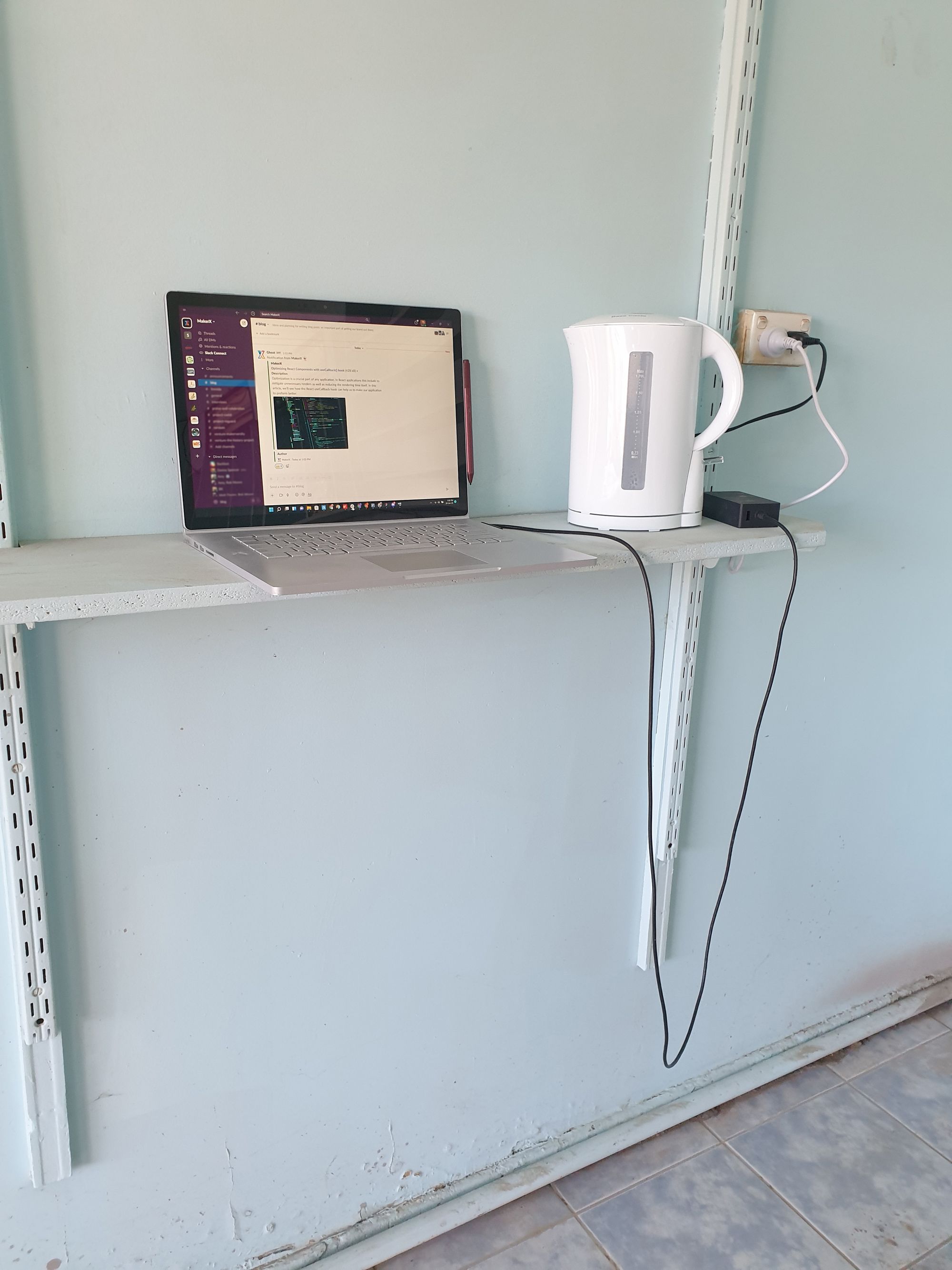A shelf with a laptop and kettle