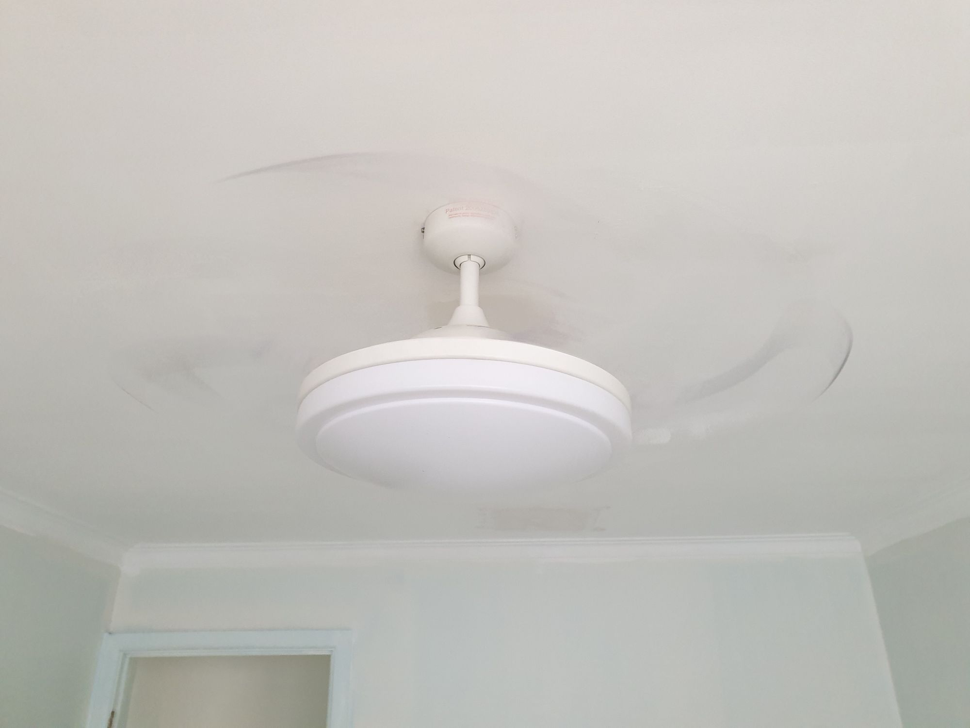 Photo of the same ceiling light, with fan blades just showing