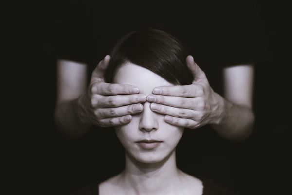 A photo of a woman with a pair of hands over her eyes